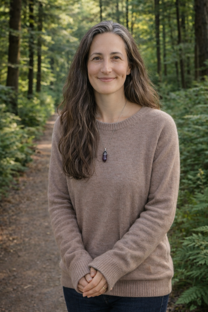 Woman standing outdoors on a wooded trail.